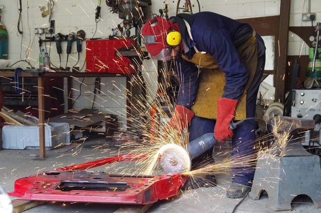 Ptlolemy Elrington trabajando en su taller con una puerta de coche de desguace